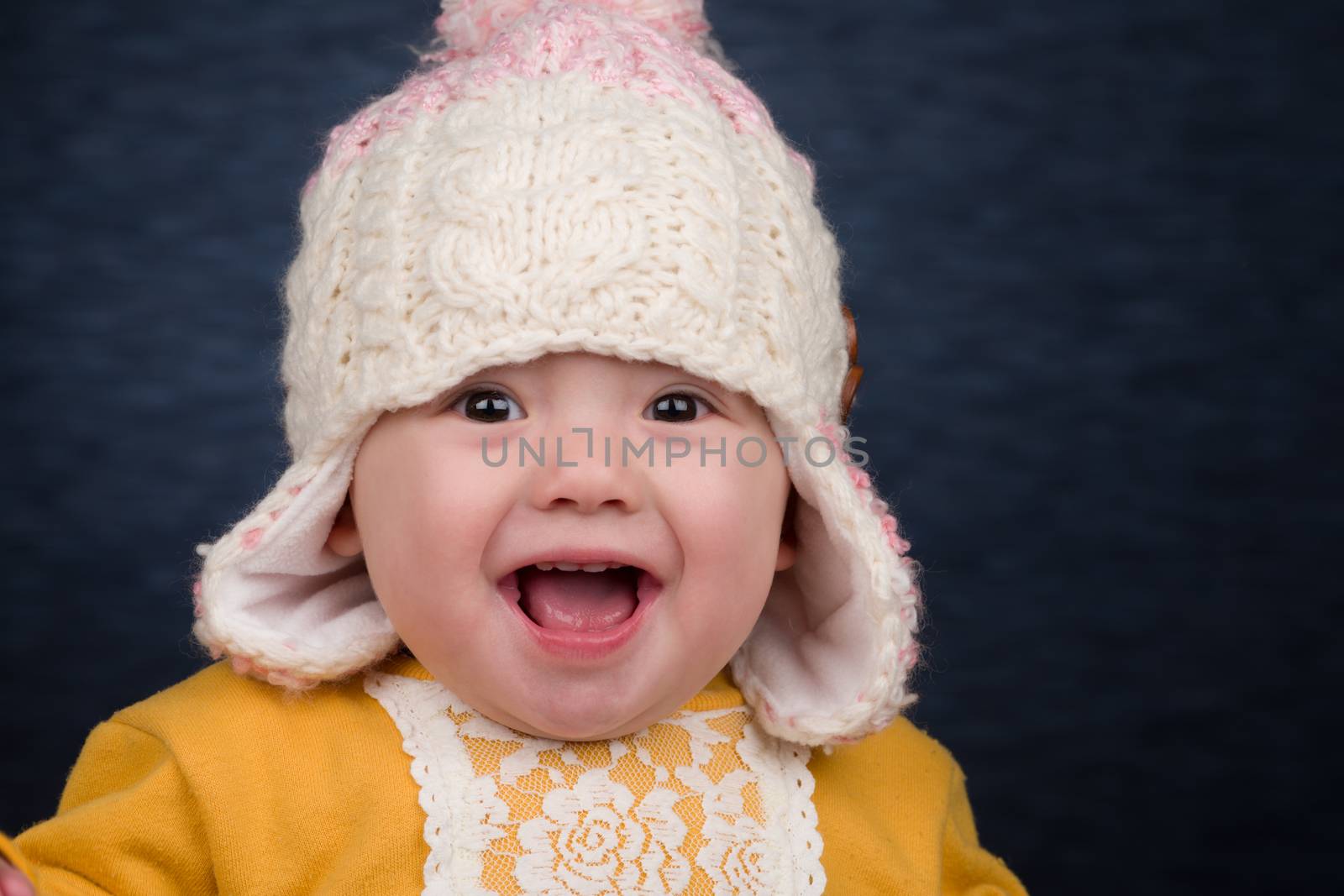 A smiling baby girl wearing a knit winter hat.
