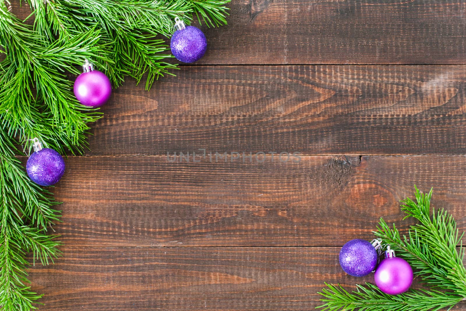 Christmas fir tree with decoration on dark wooden board background. Border art design with Christmas tree and purple baubles. Xmas and new year concept with copy space