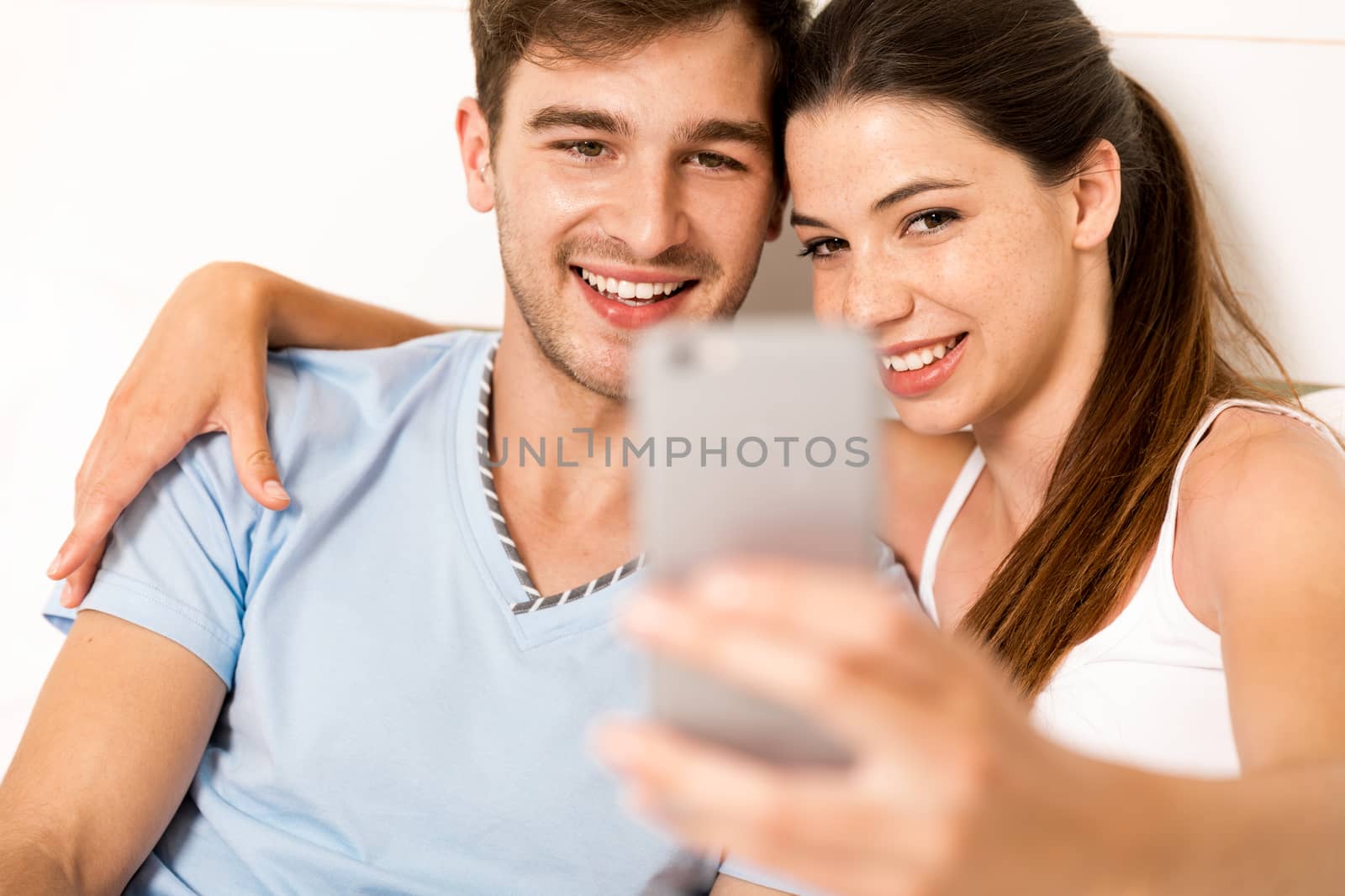 Young couple on bed making selfies with a phone