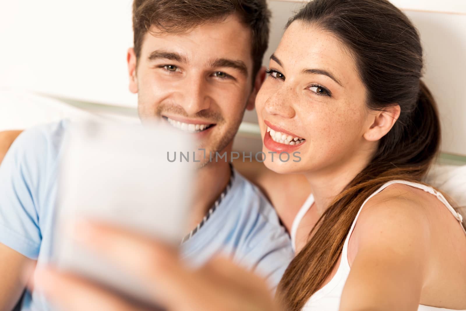 Young couple on bed making selfies with a phone