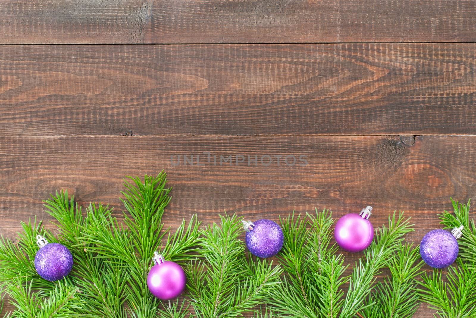 Christmas fir tree with decoration on dark wooden board background. Border art design with Christmas tree and purple baubles. Xmas and new year concept with copy space