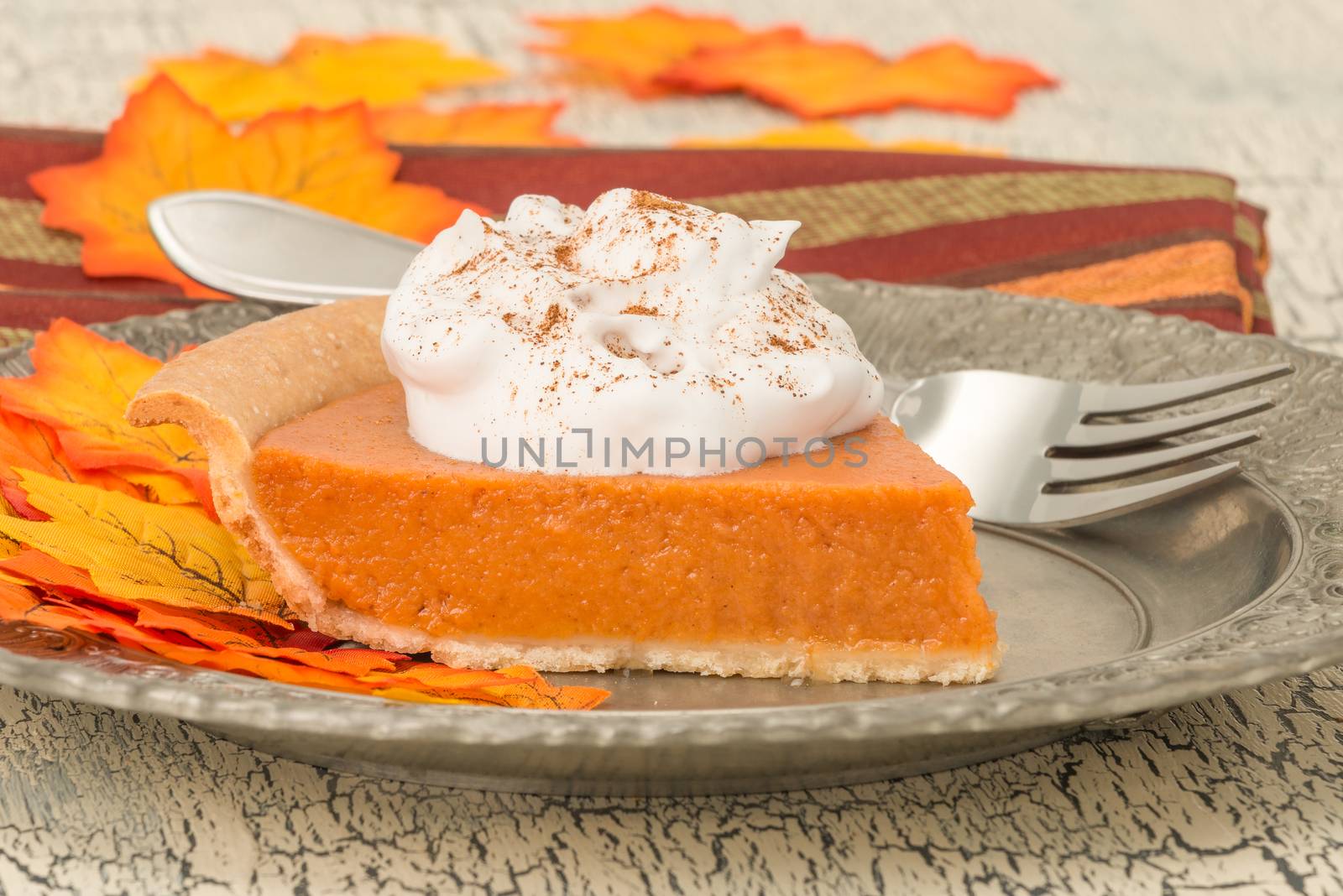Serving of pumpkin pie with whipped cream photographed closeup.
