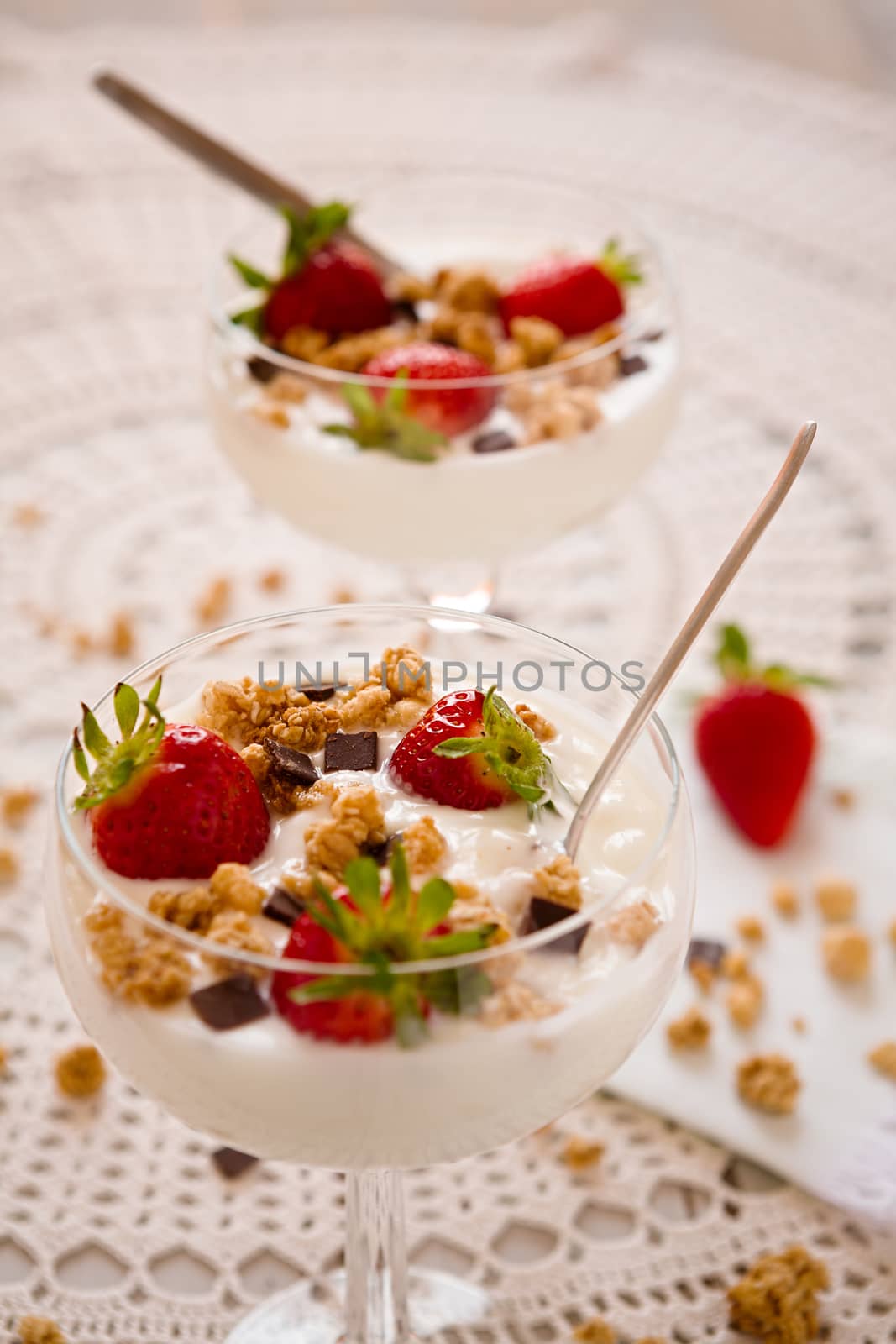 Dessert with strawberries cereals and chocolate flakes inside a cup with plain yogurt