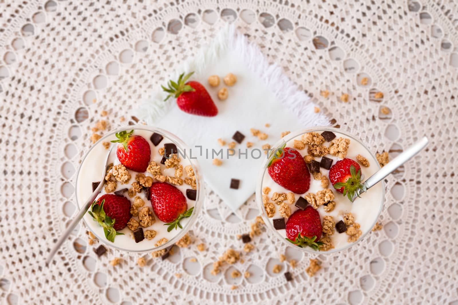 Strawberries cereals and chocolate flakes inside the plain yogurt seen from above