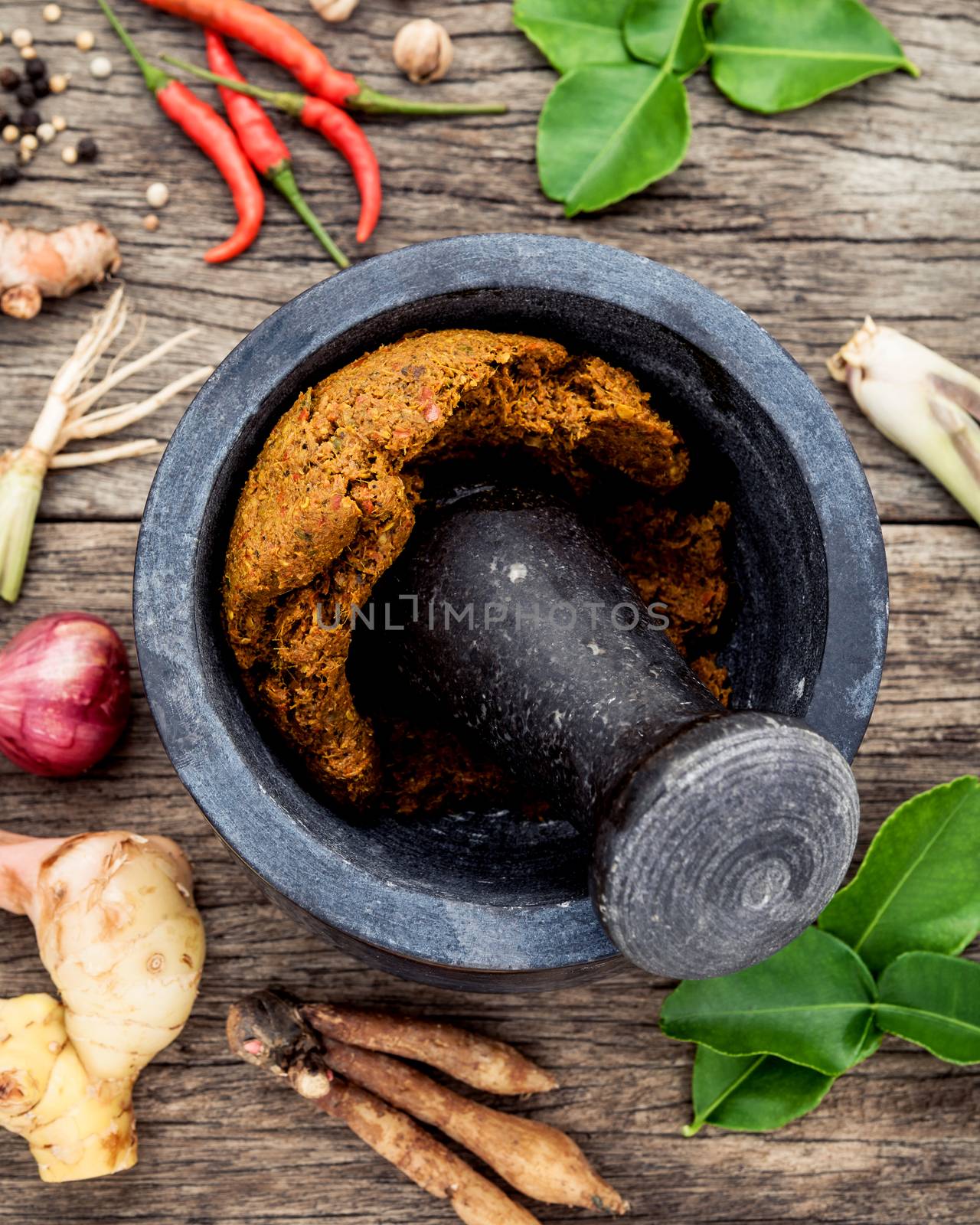 Assortment of Thai food Cooking ingredients and Paste of thai popular food red curry  with mortar and pestle on rustic wooden background. Spices ingredients chilli ,pepper, garlic,galanga lemongrass and Kaffir lime leaves .