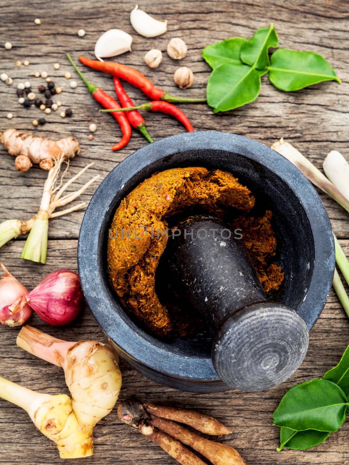 Assortment of Thai food Cooking ingredients and Paste of thai popular food red curry  with mortar and pestle on rustic wooden background. Spices ingredients chilli ,pepper, garlic,galanga lemongrass and Kaffir lime leaves .