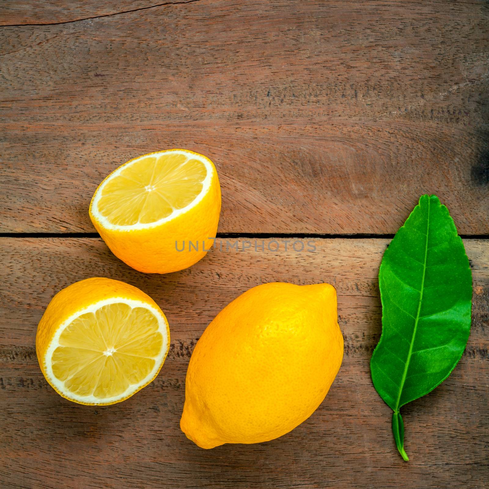 Fresh lemons and  lemons leaves on rustic wooden background. Fresh lemons and lemon slice on wooden table with flat lay.  Fresh citrus fruit background.