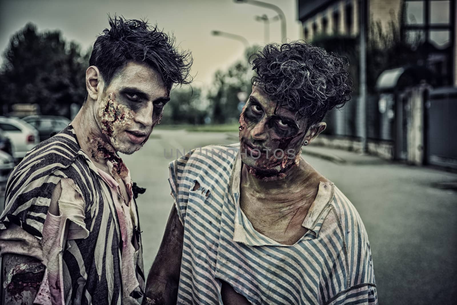 Two male zombies standing in empty city street looking at camera