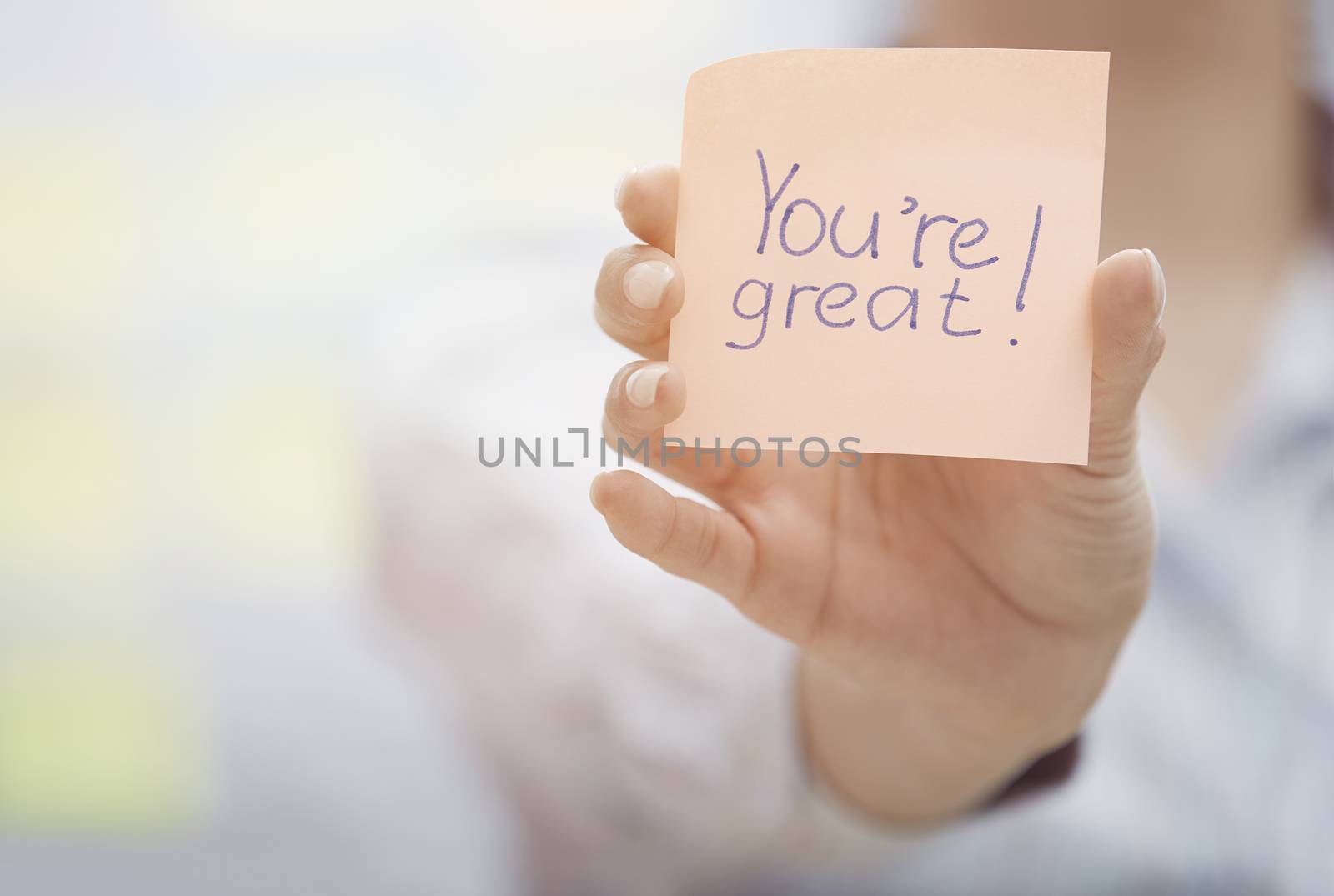 Woman holding sticky note with You are great text