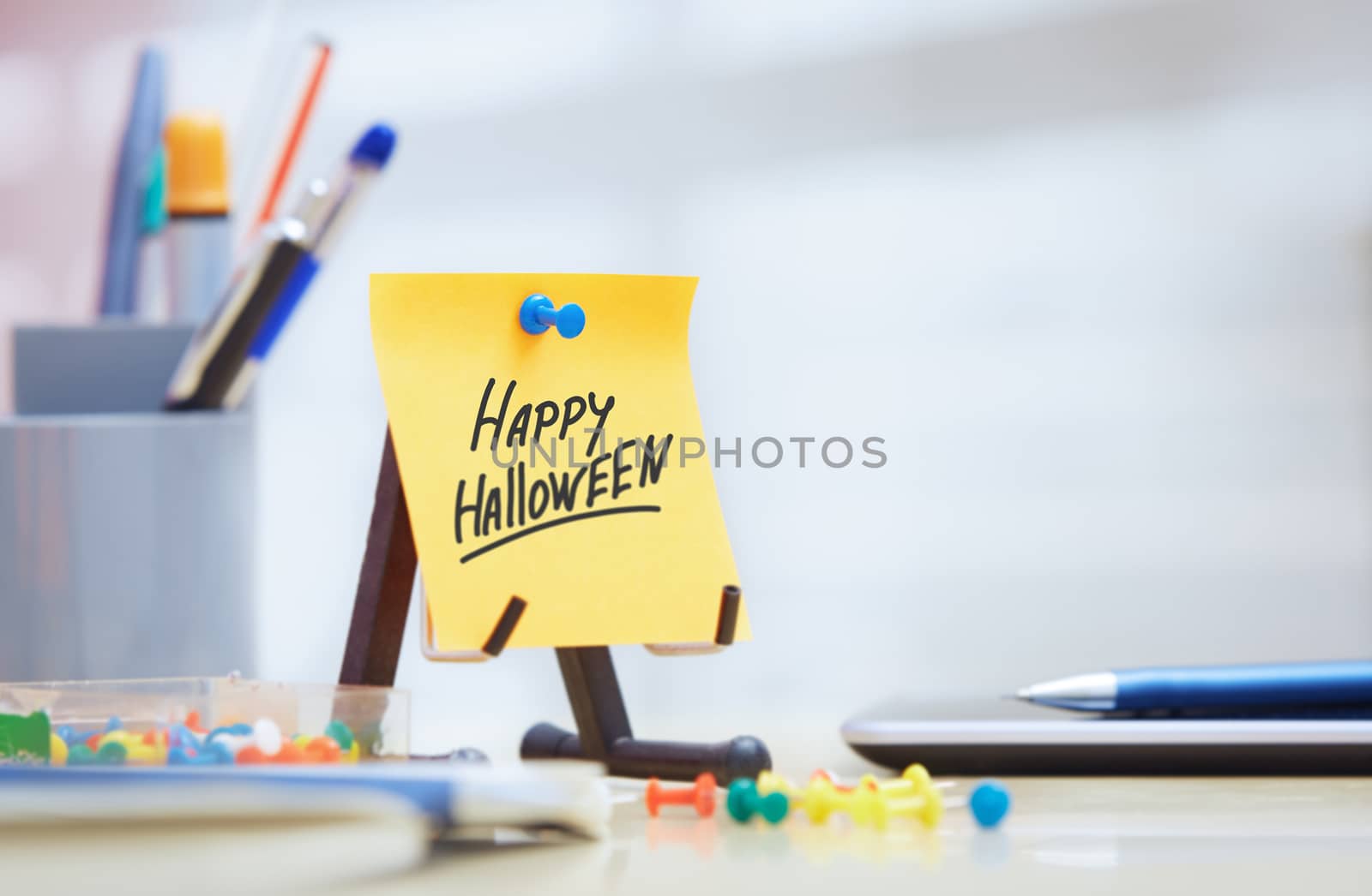 Hand taking sticky note with Happy Halloween text