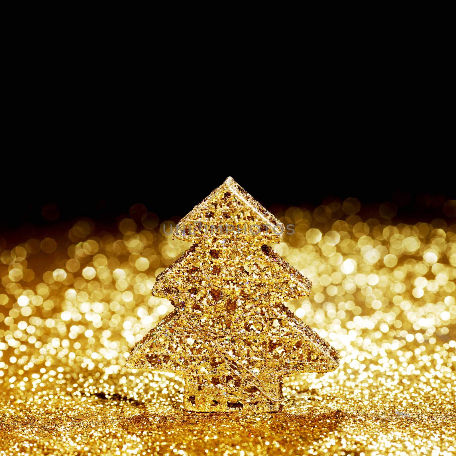 Beautiful golden decorative christmas tree on golden glitter background with black copy space