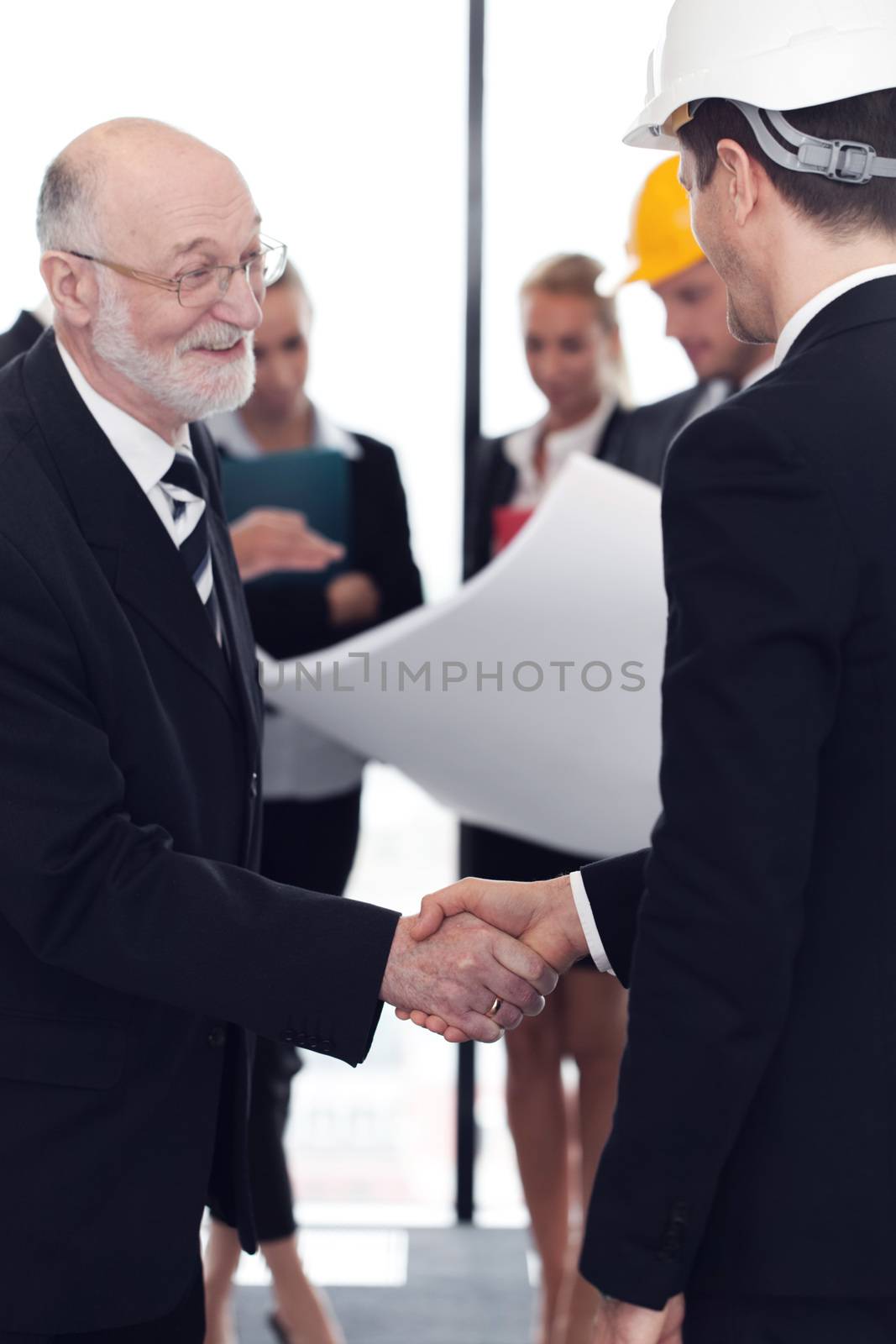 Handshake of architect and investor, business team with blueprint on background