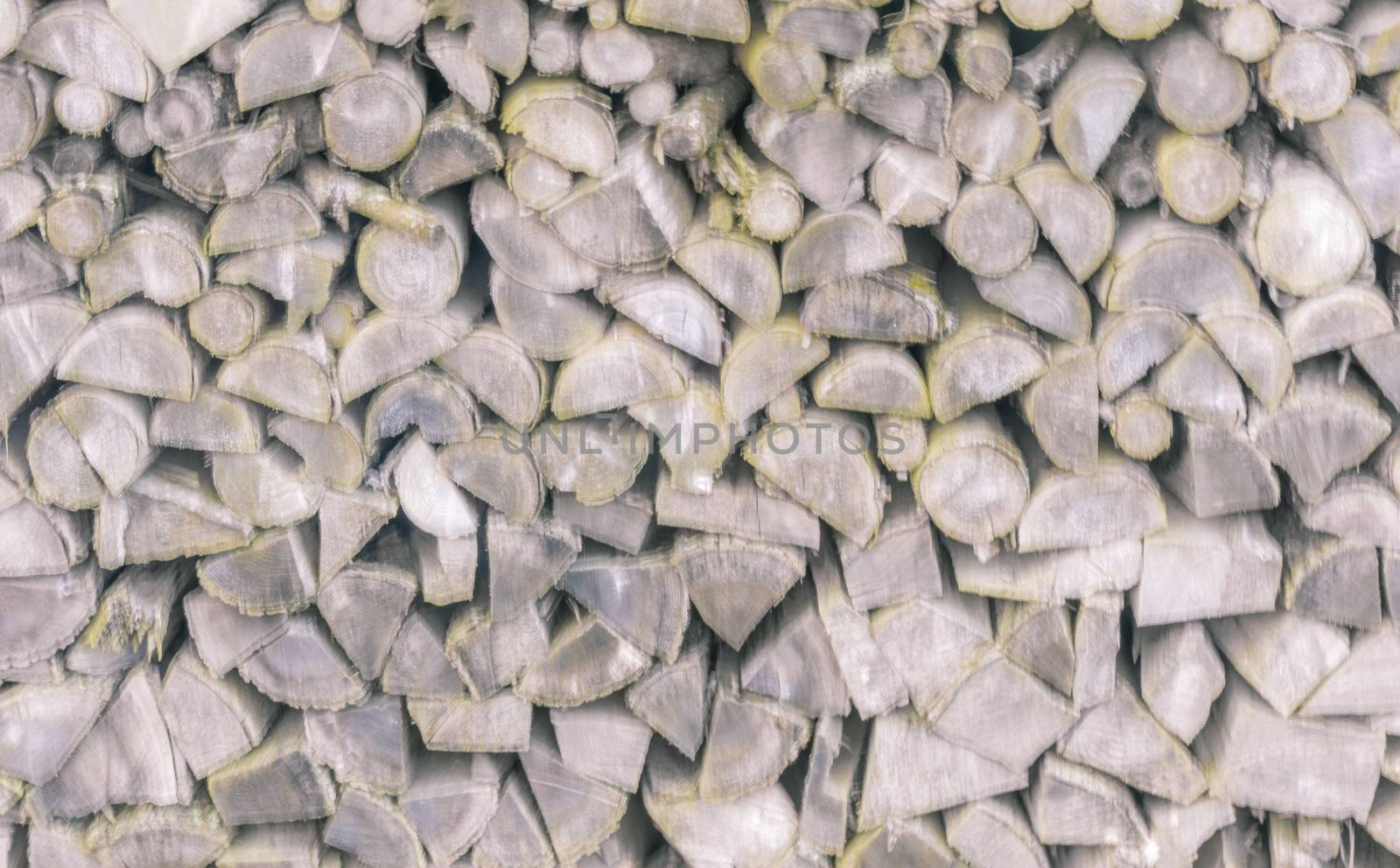 Blurry background with a pile of chopped firewood logs in different shapes