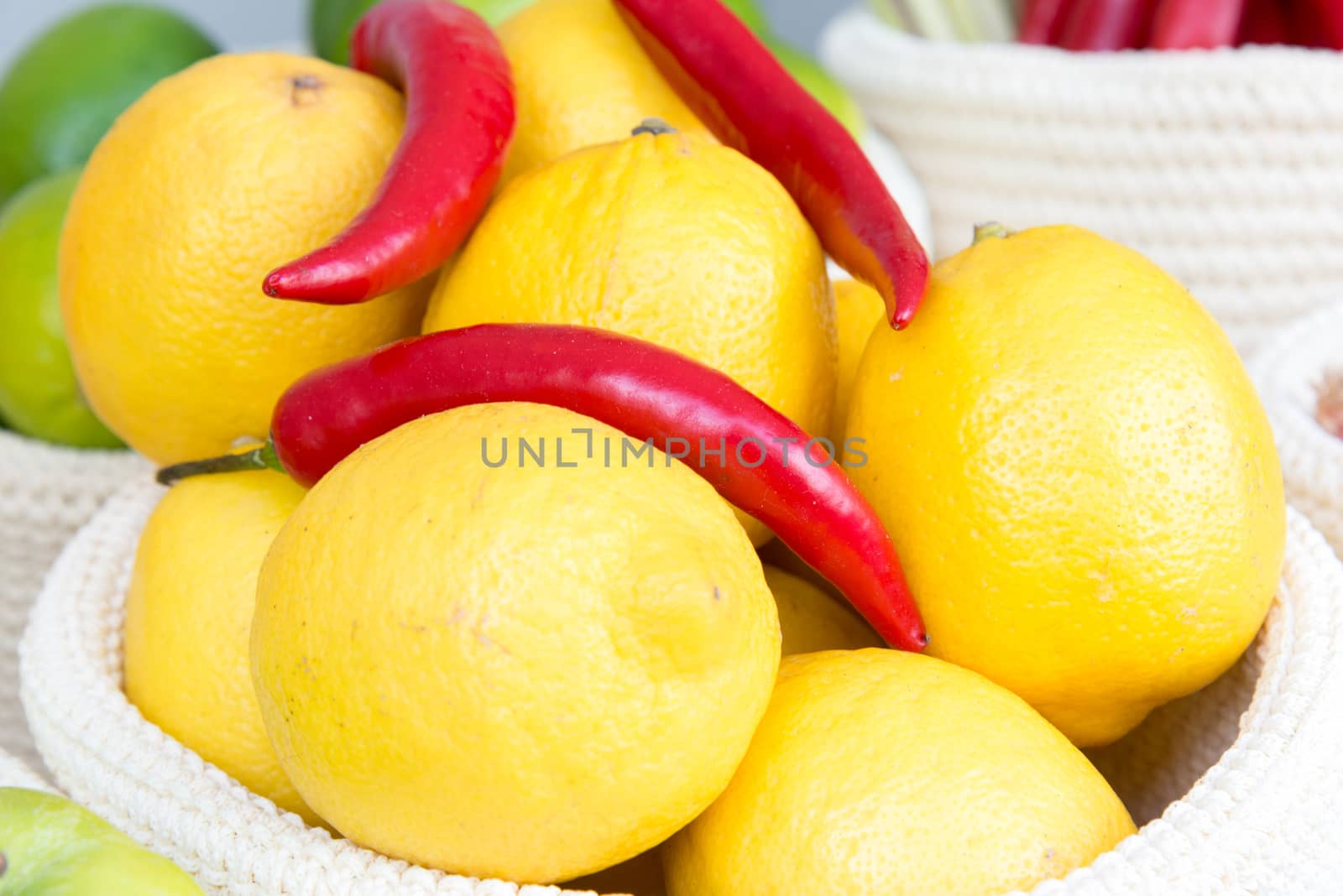 lemons and chili peppers in a wicker basket close-up by vlaru