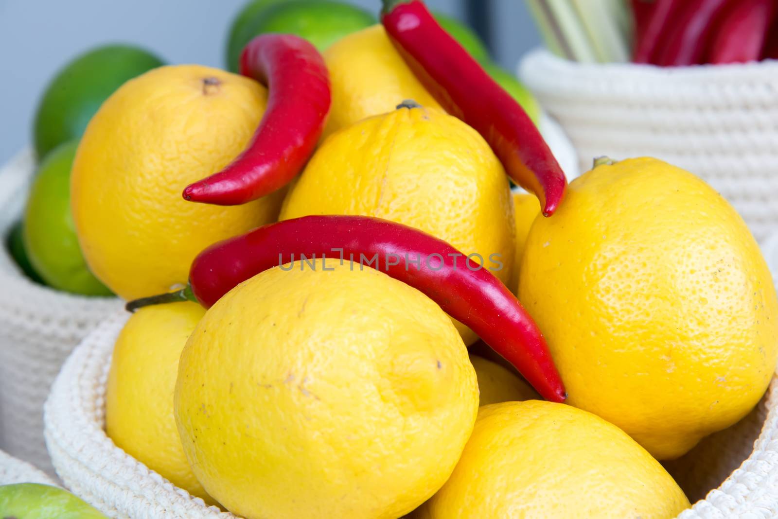 lemons and chili peppers in a wicker basket close-up by vlaru