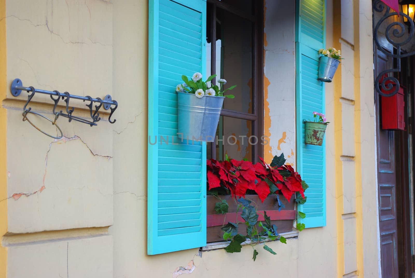 white stone facade with blue shutters and flowers from the side by evolutionnow