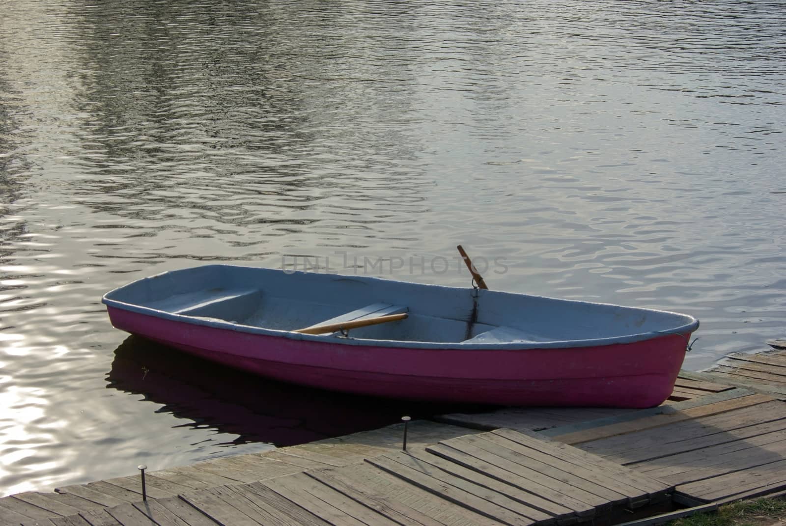 a pink rowing boat moored by the jetty pier on a lake