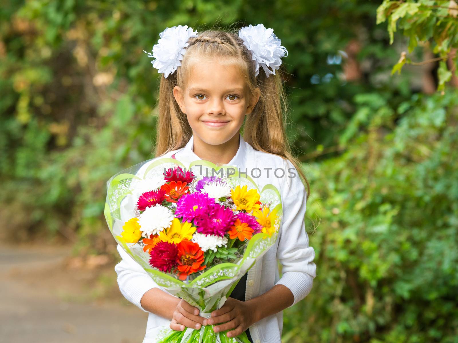 Up portrait of a seven-year school girl with a bouquet of flowers