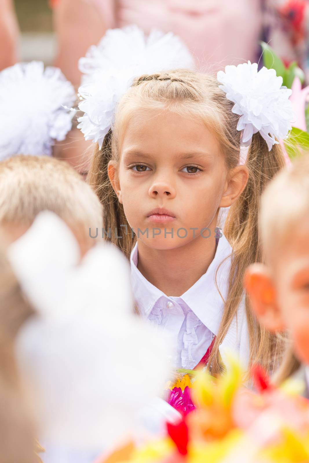 First grader tired of classmates in the crowd at the first line of September