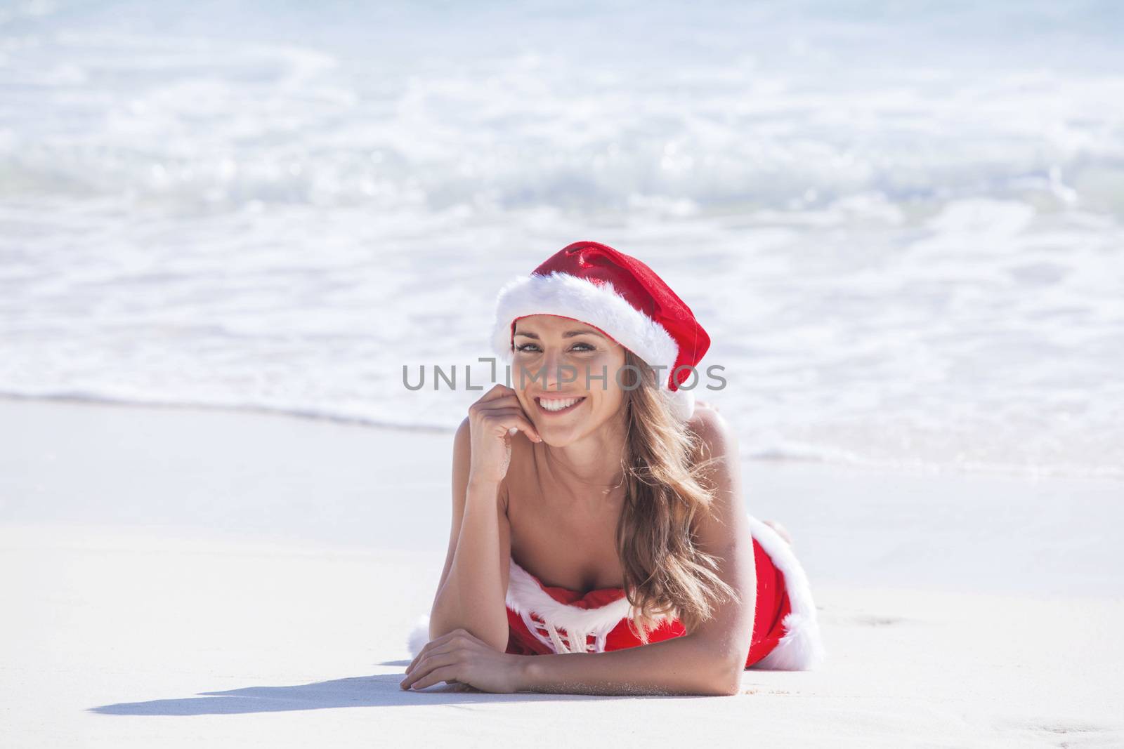 Beautiful woman in Mrs. Claus custume on tropical beach, Christmas vacations concept