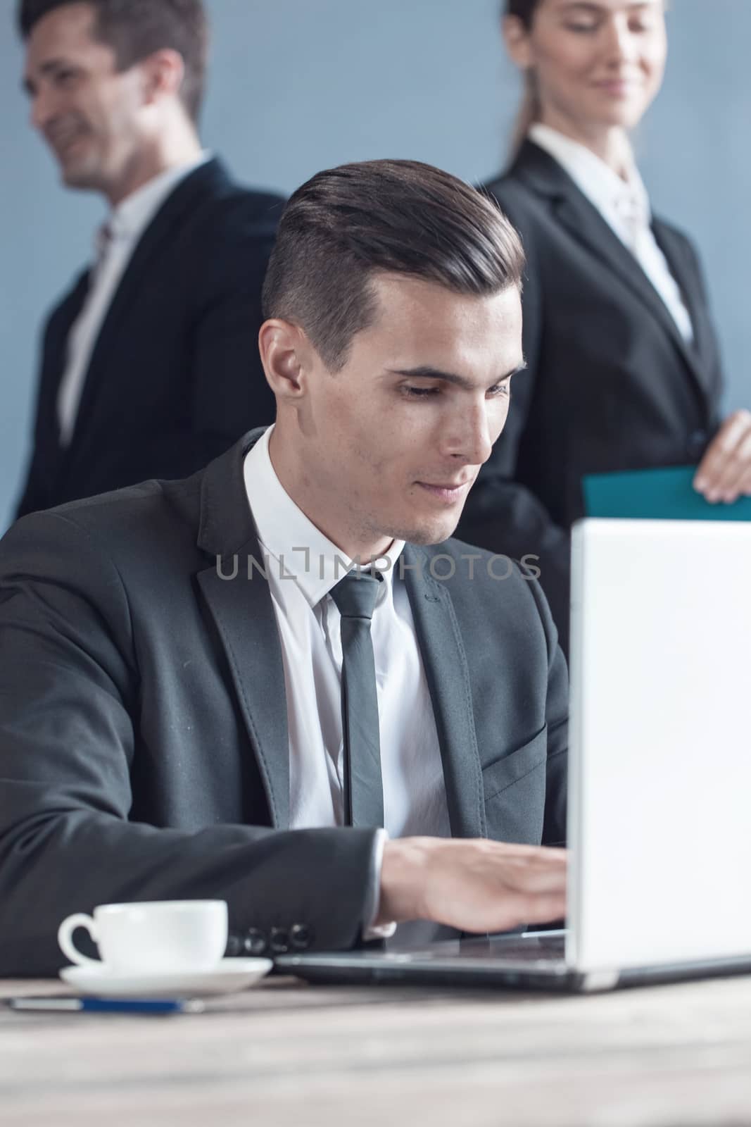 Business man using laptop in office, business team on background