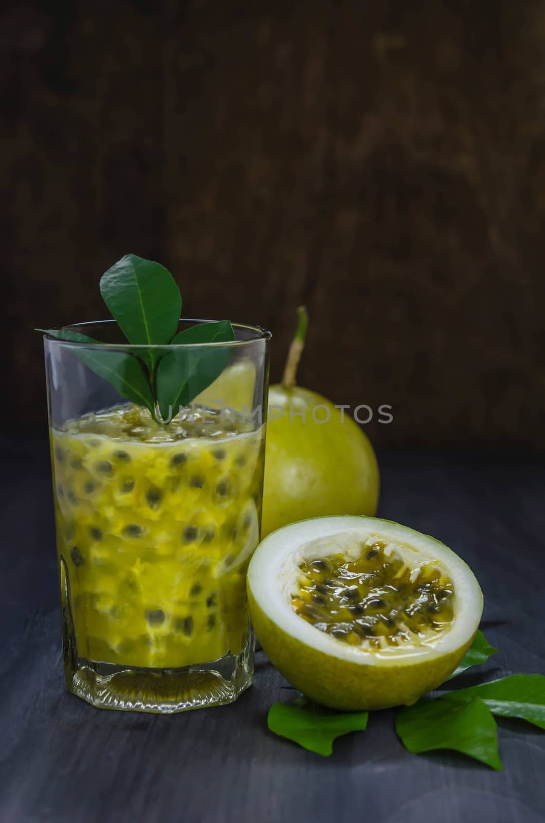 Fresh passion fruit juice in glass with passion fruits over wooden background , still life