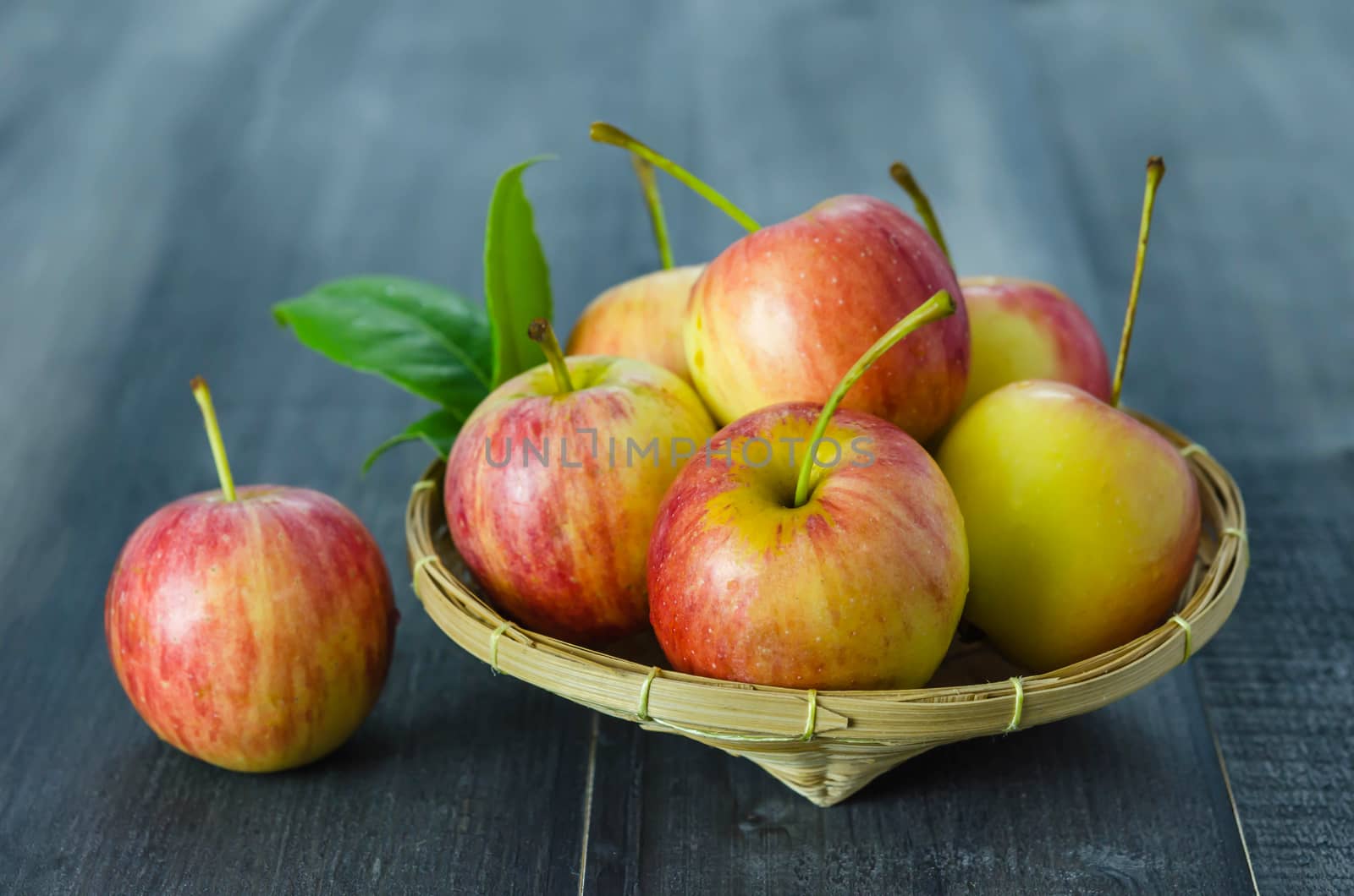 Red and yellow apple  with bamboo basket , organic fresh fruit on wooden background