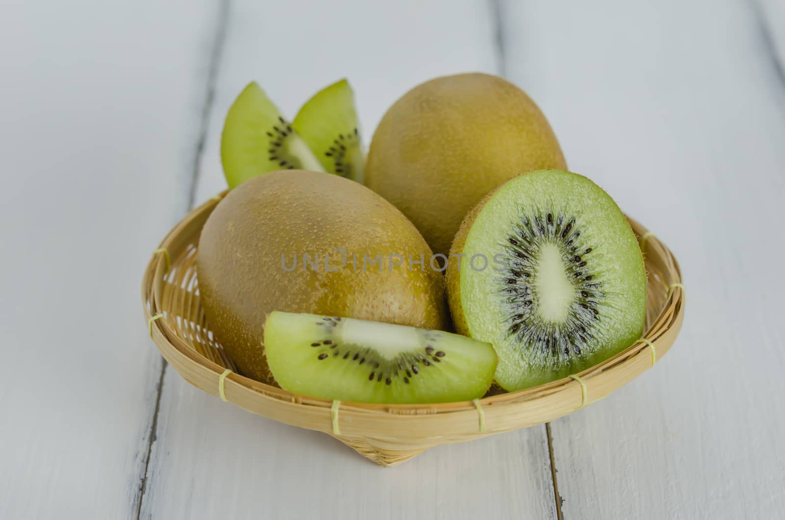 kiwi fruit and sliced with bamboo basket on wooden background