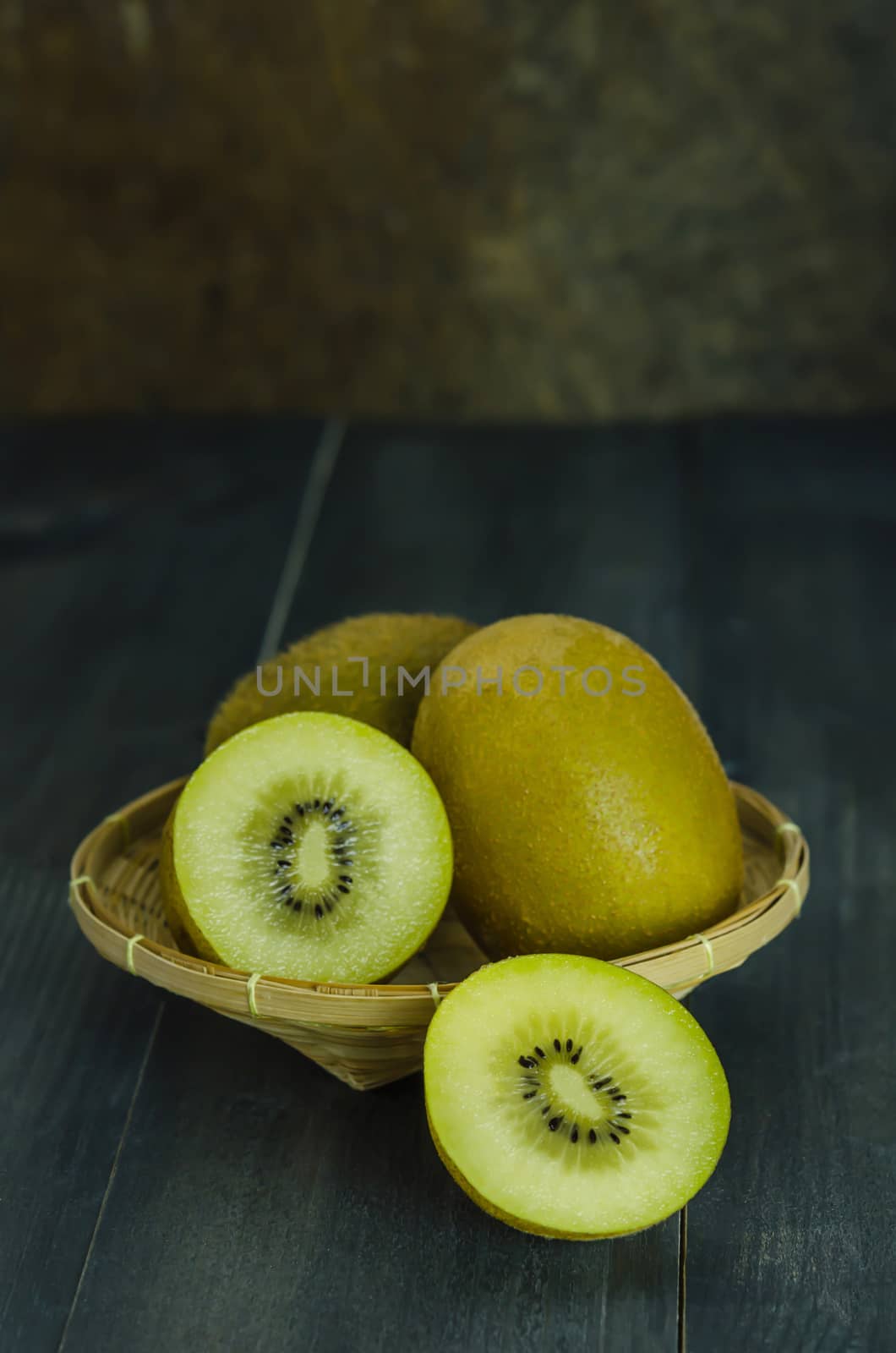 kiwi fruit and sliced with bamboo basket on wooden background , still life