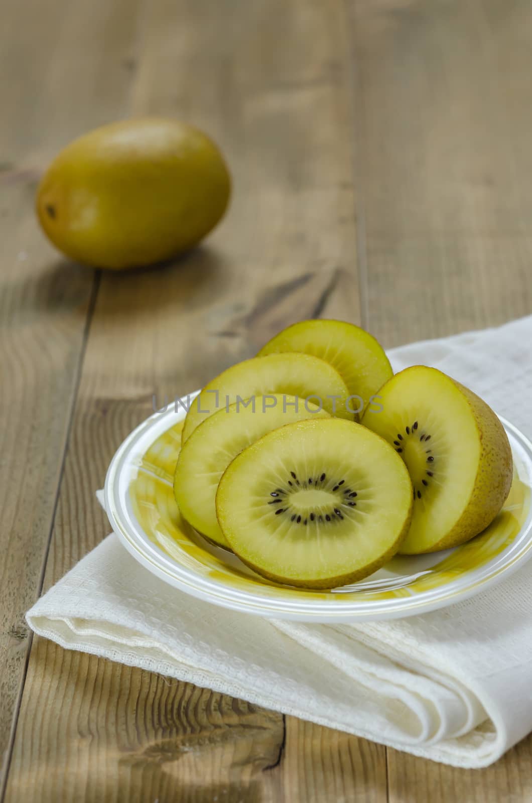 golden kiwi fruit and sliced on dish over wooden background