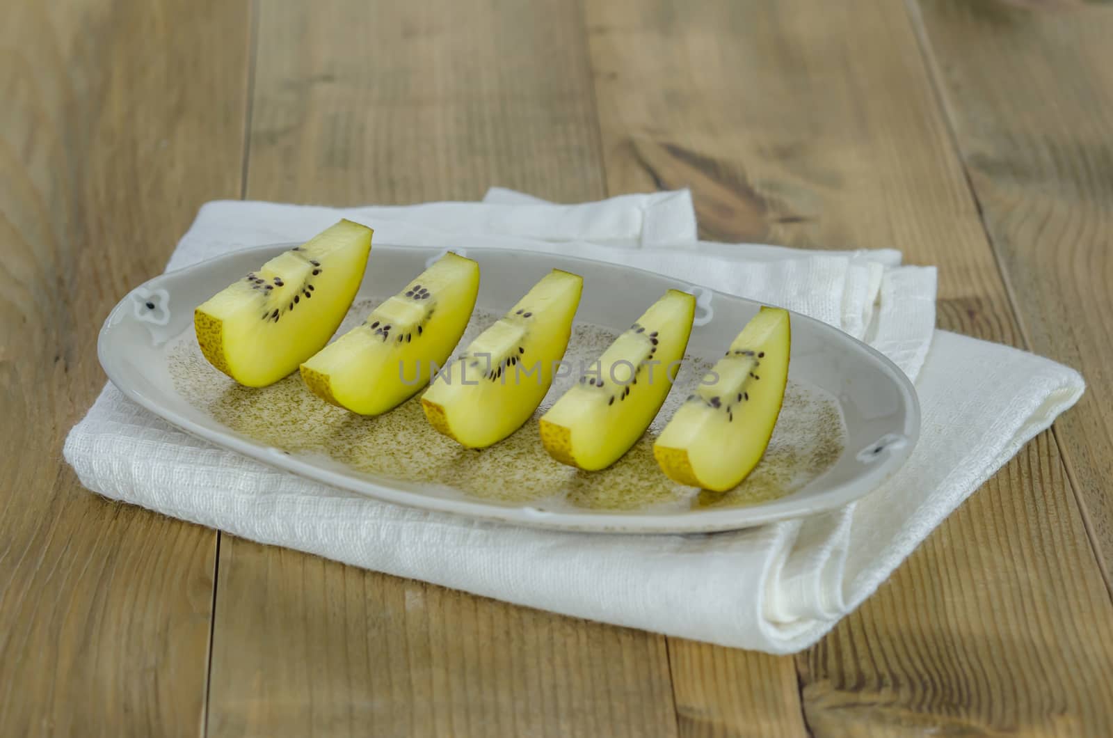 sliced of golden kiwi fruit  on dish over wooden background
