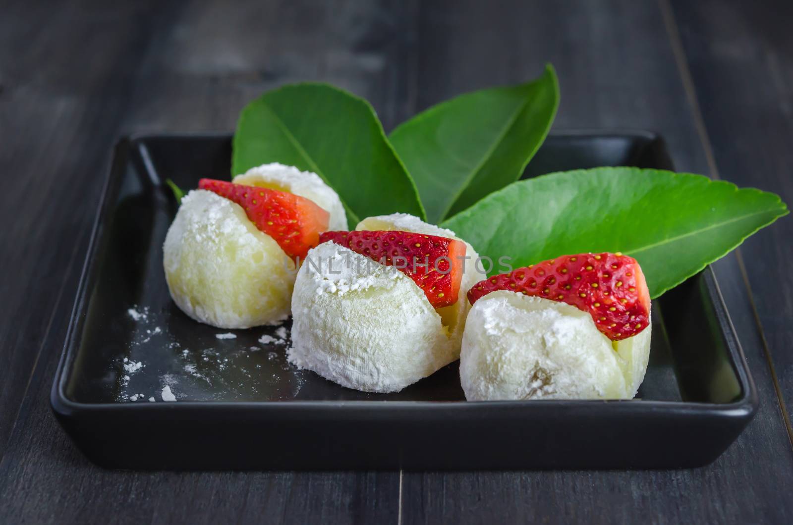 Strawberry Daifuku Mochi Japanese dessert on black dish over wooden background