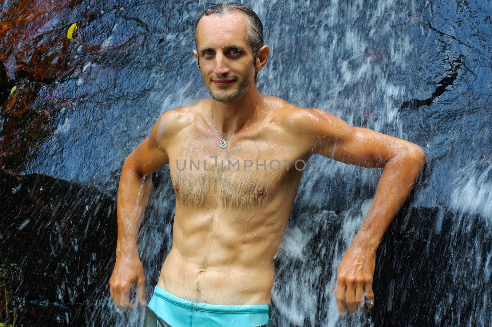 a man taking a relaxing shower under a waterfall outside