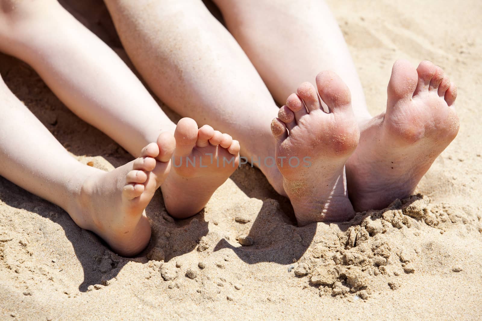 Feet of mother and her child in the sand