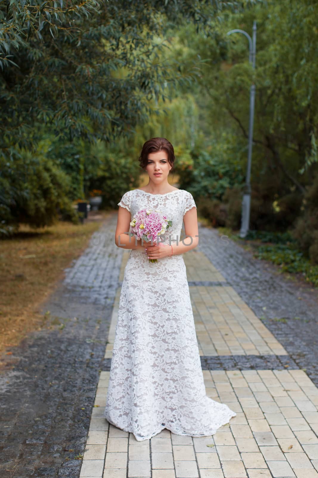 Bride in the park in the alley on a rainy day