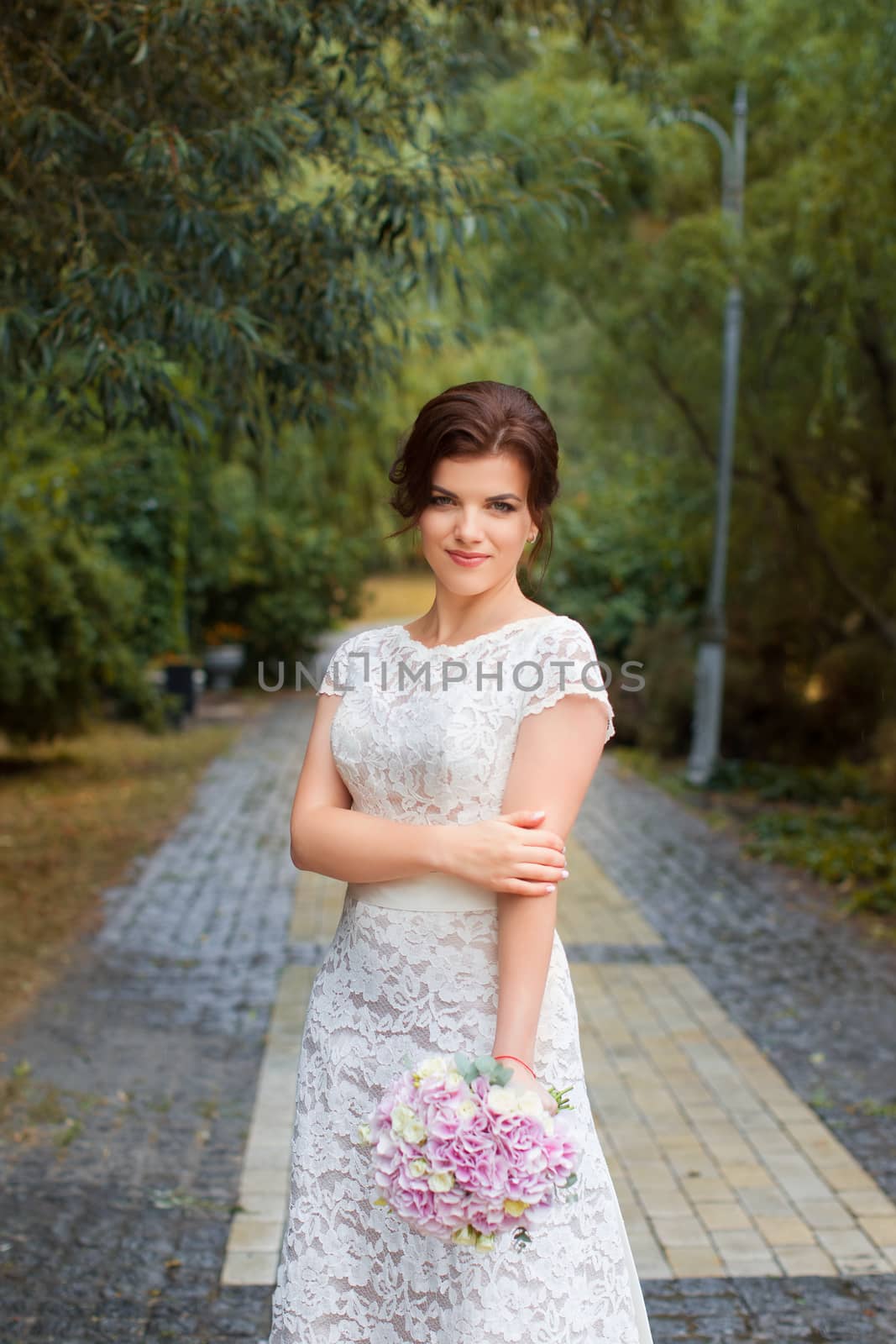 Bride in the park in the alley on a rainy day