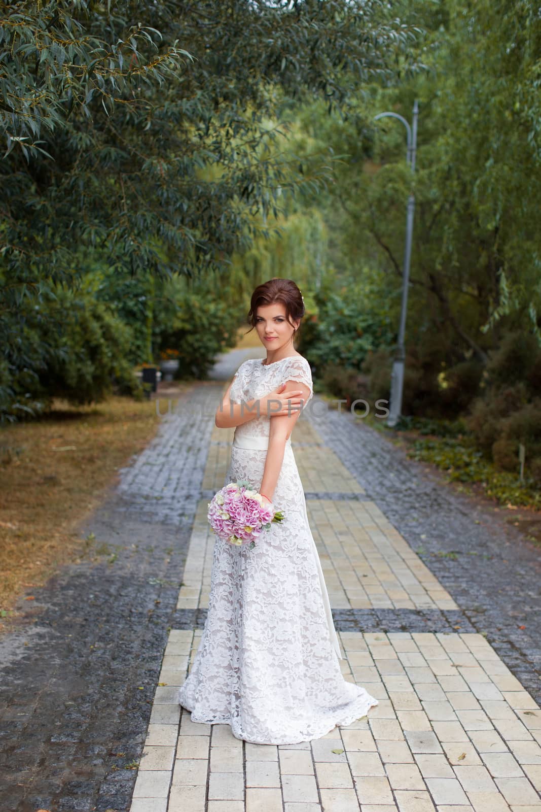 Bride in the park in the alley on a rainy day