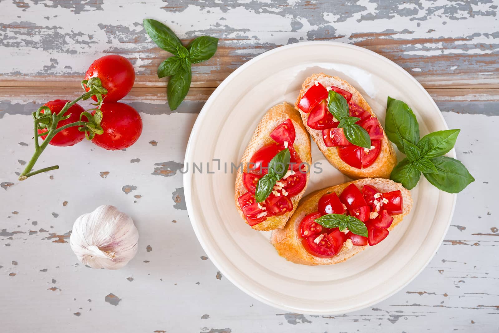 Italian bruschetta with tomato, basil and garlic on a plate seen from above