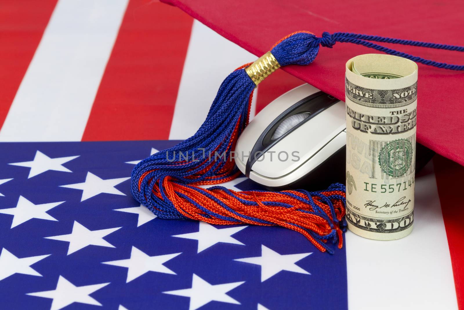 Graduation cap with tassle placed with computer mouse and dollar currency on American flag pattern.  Concept symbolized is the higher salary and job opportunities of degree associated with electronics and digital knowledge.  Computer science degree holds benefits reflected in national education STEM policy.  