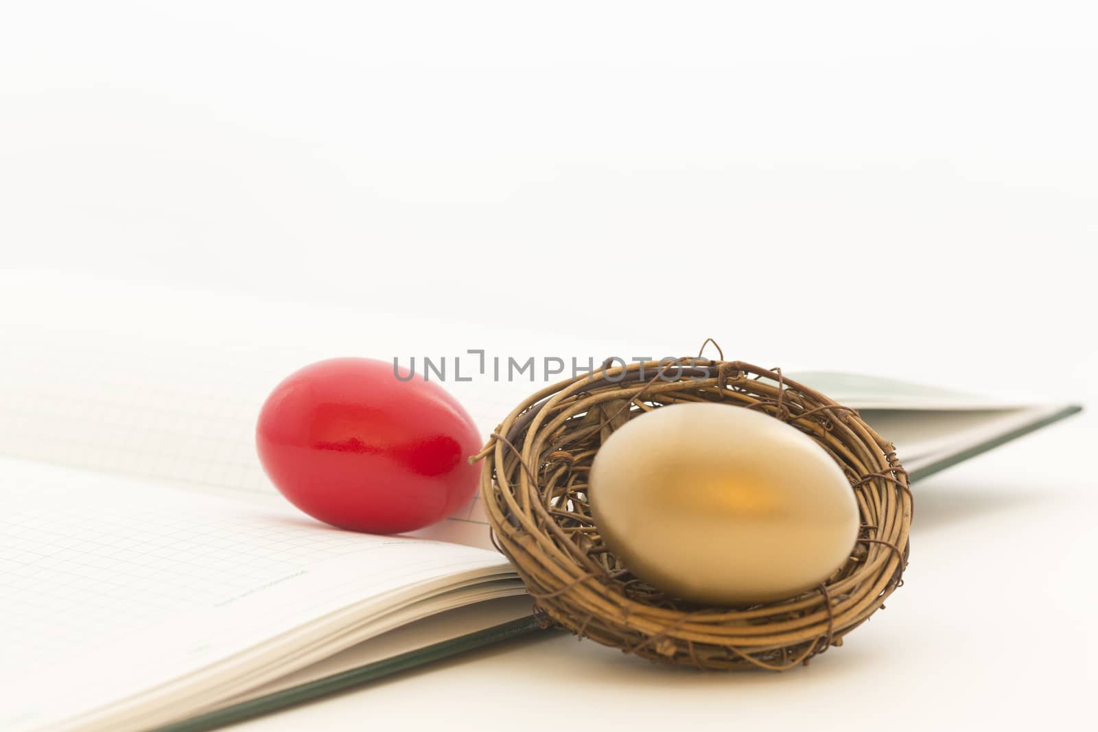 Red and gold nest eggs on green ledger reflect risk and opportunity in investment environment for businesses and individual investors.  Copy space on horizontal image. 
