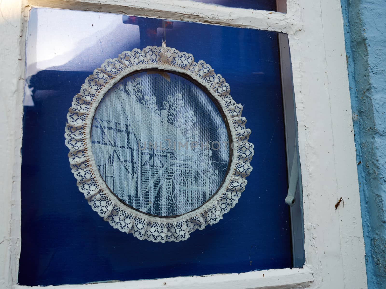 Traditional European handmade crochet lace decoration shaped as a circle in a window    