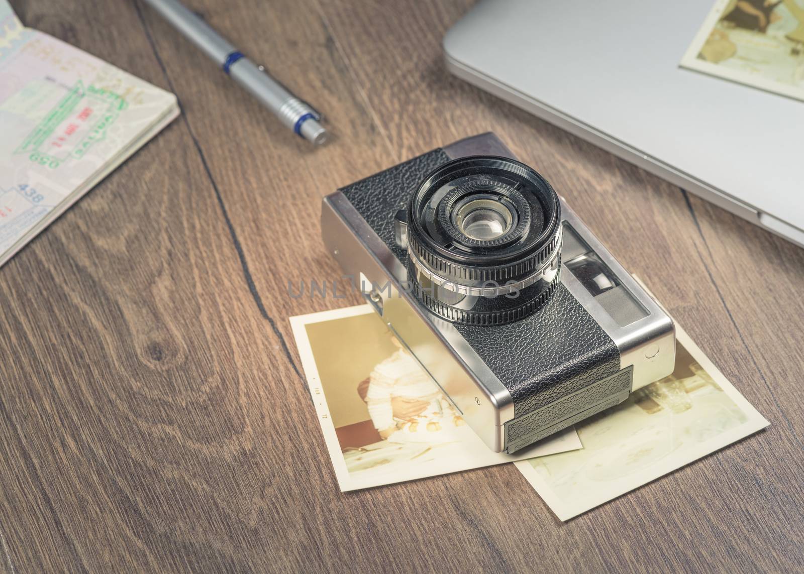 Vintage image with old Camera,old photo,laptop,pen and passport on wood table.