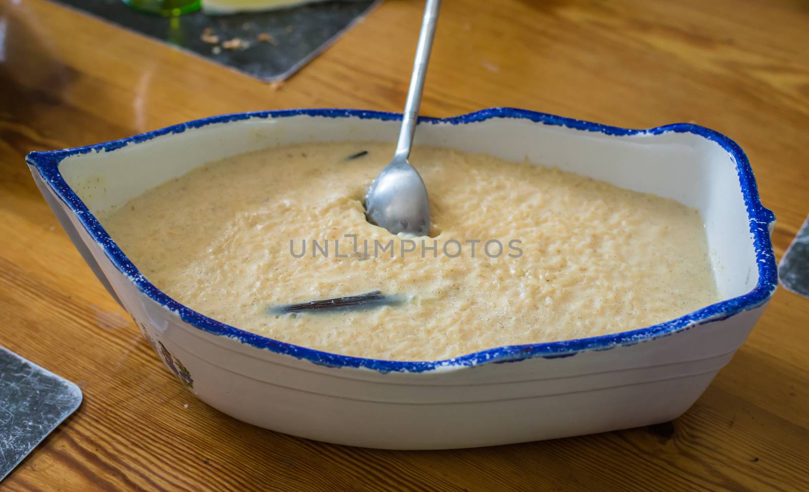 Creamy rice pudding with vanilla bean in ceramic vessel in the form of a boat on the table