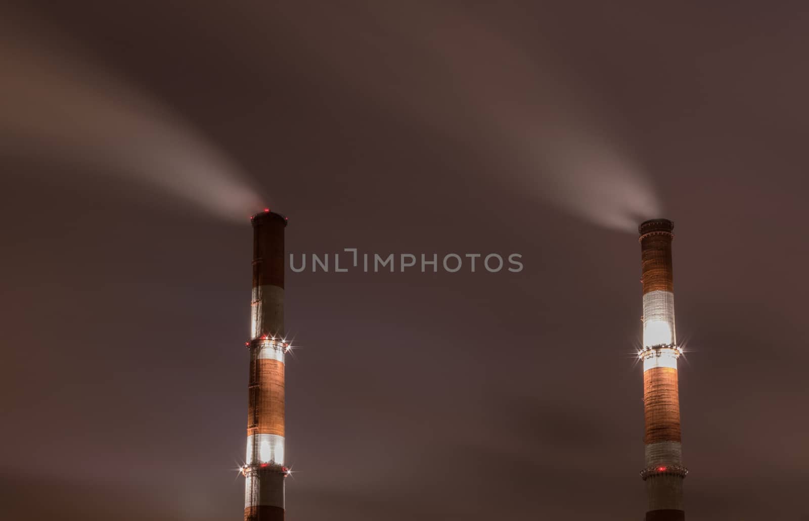 Two smoke stack against sky at night by dpetrakov