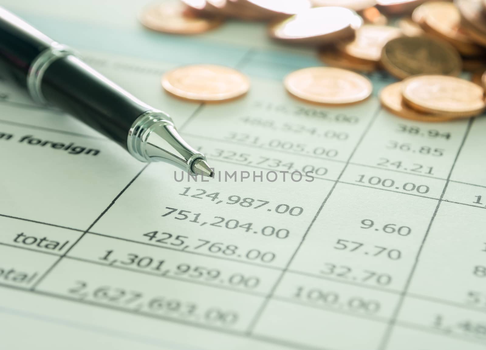 pen and golden coins on summary report. selective focus.