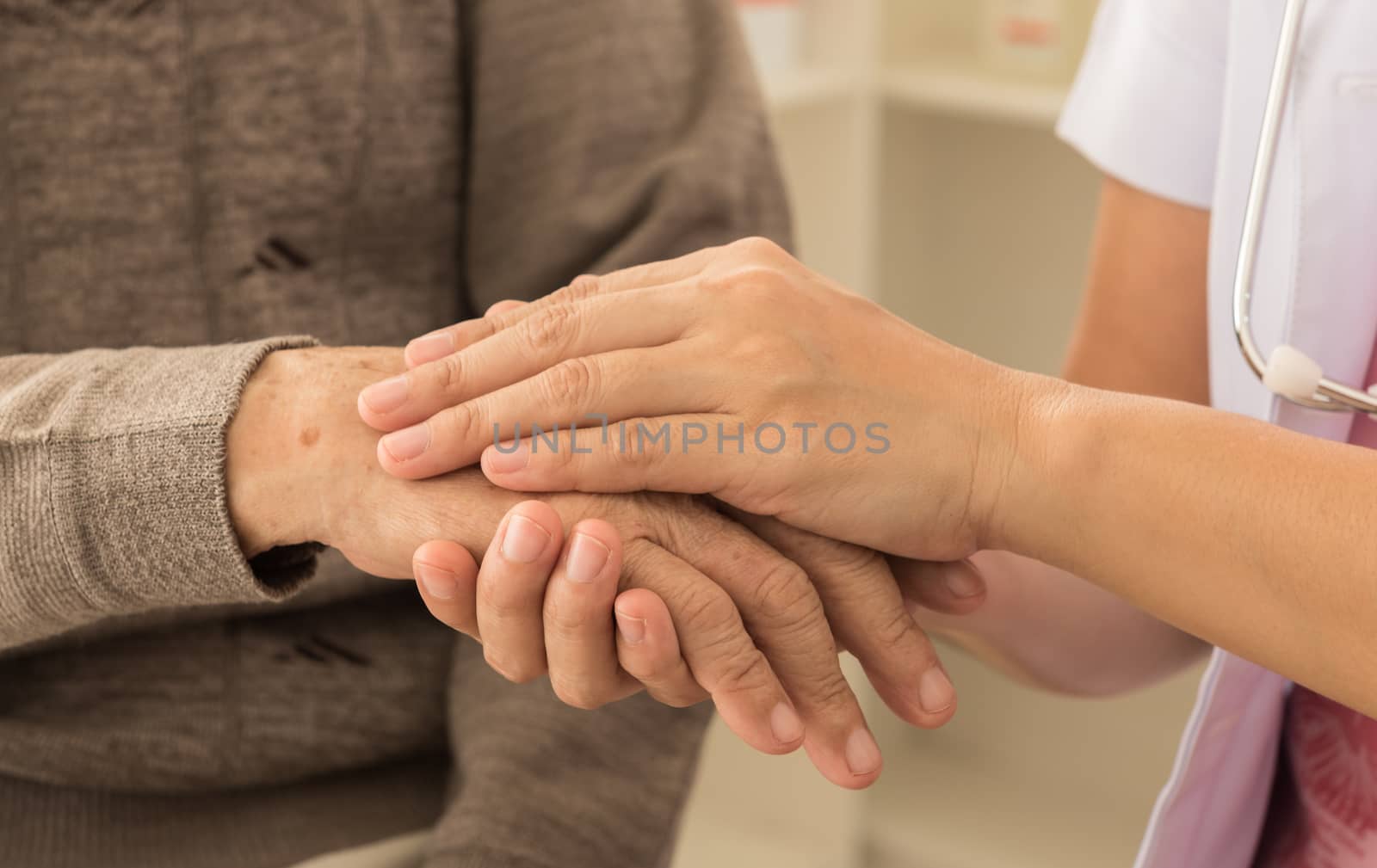 medical doctor holding senior patient's hands and comforting.