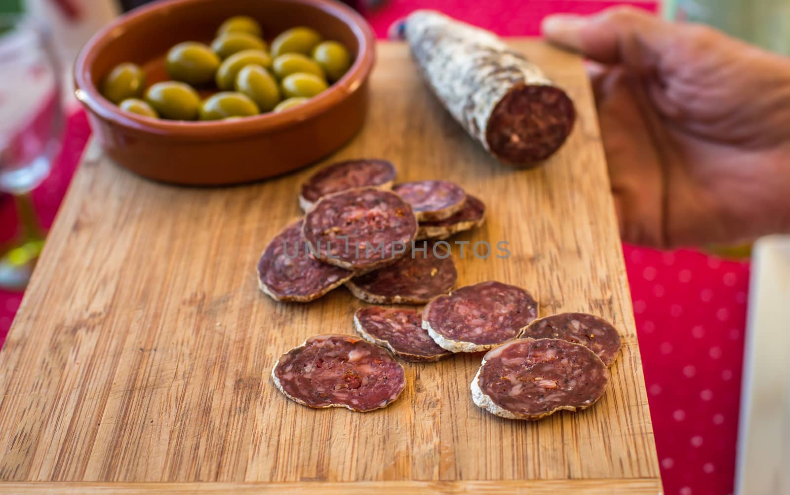 sliced sausage with green olives on a wooden board on the table