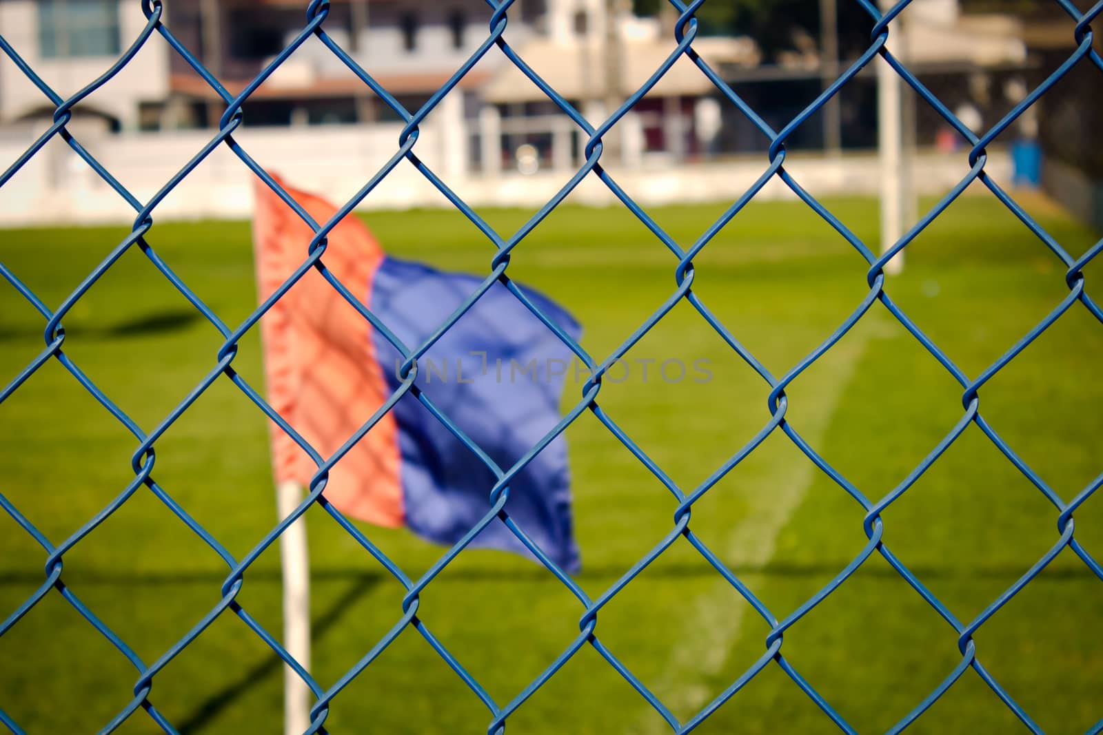 Red and blue flag though fence in soccer field