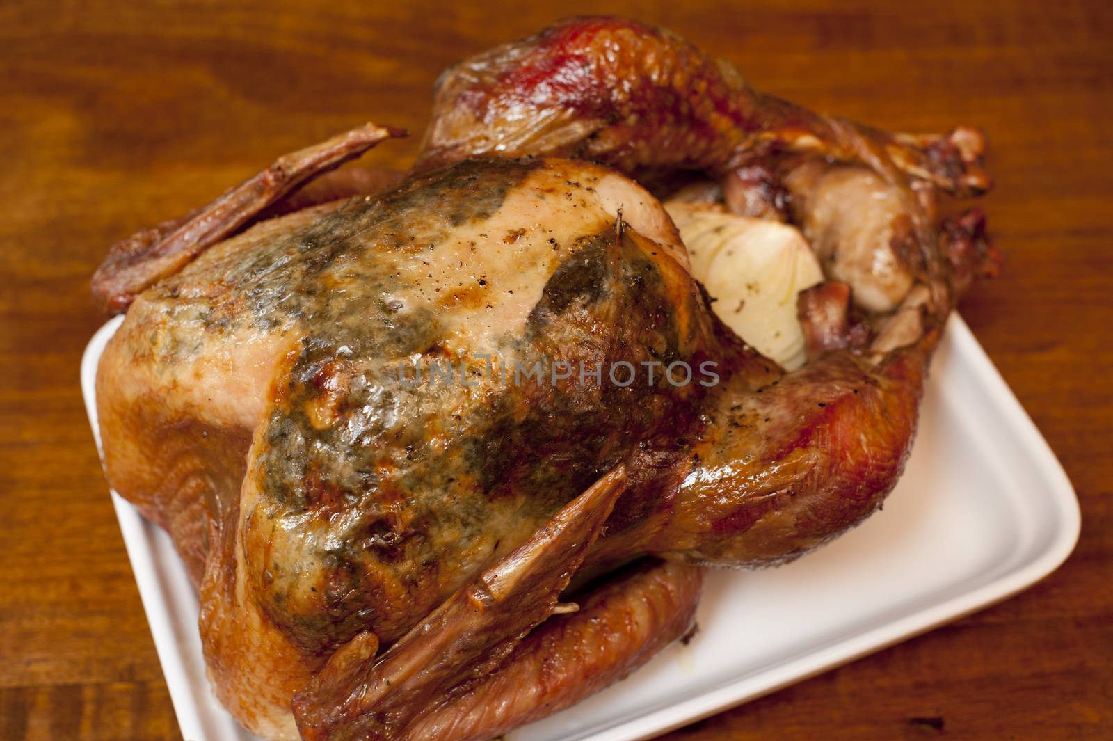 Delicious whole marinated spicy grilled or roast chicken on a plate ready to be carved for dinner, high angle view