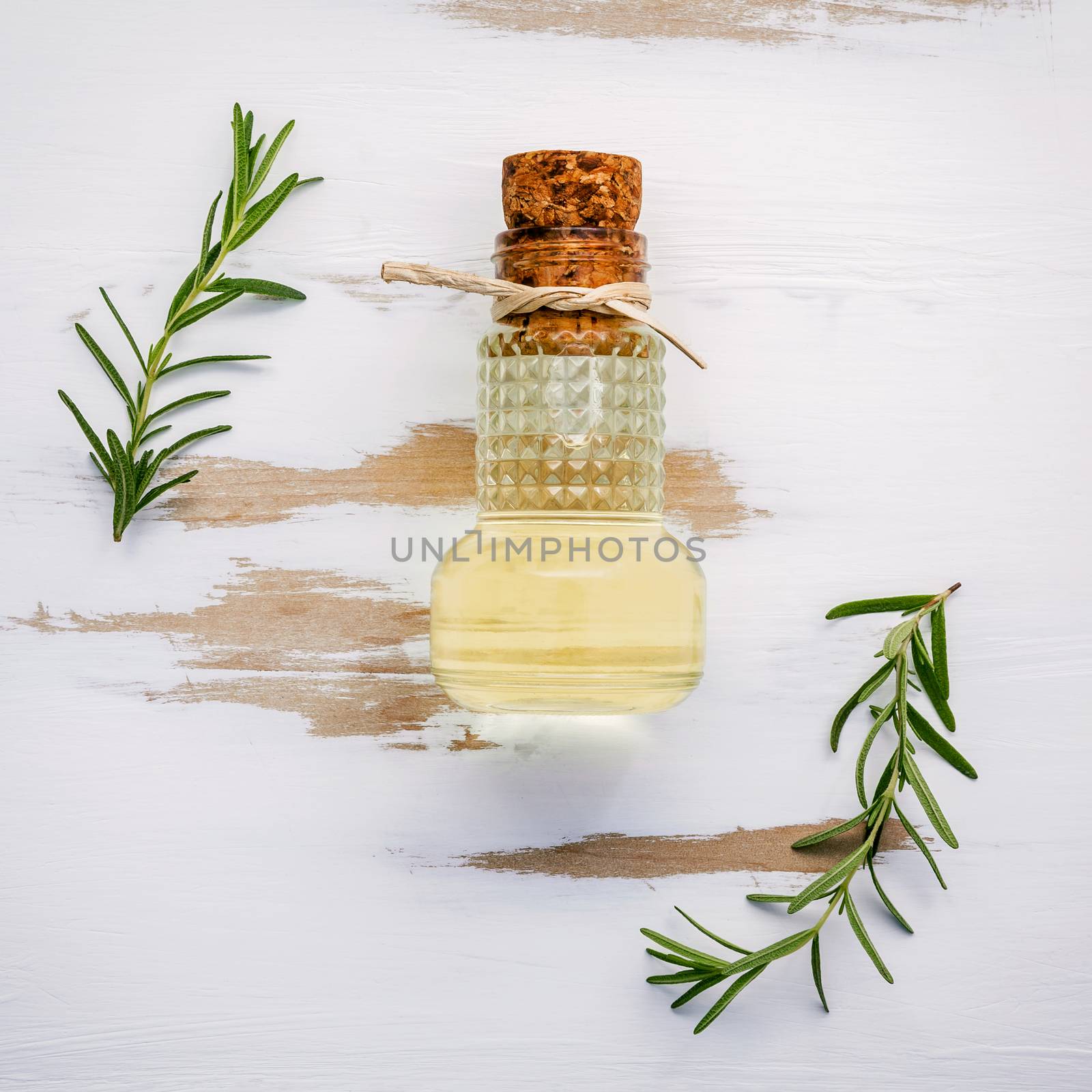 Bottle of extra virgin olive oil with rosemary. Sprigs of rosemary and olive oil set up on white shabby wooden background . Fresh branch of rosemary with bottle essential oil with flat lay on white table.